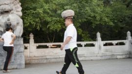 Un hombre camina con una piedra de 40 kilos en la cabeza para perder peso